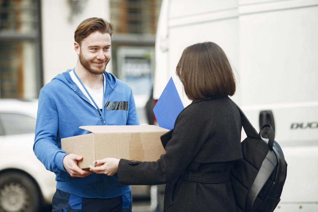 Candid moment of a deliveryman handing a package to a woman outside by a van.